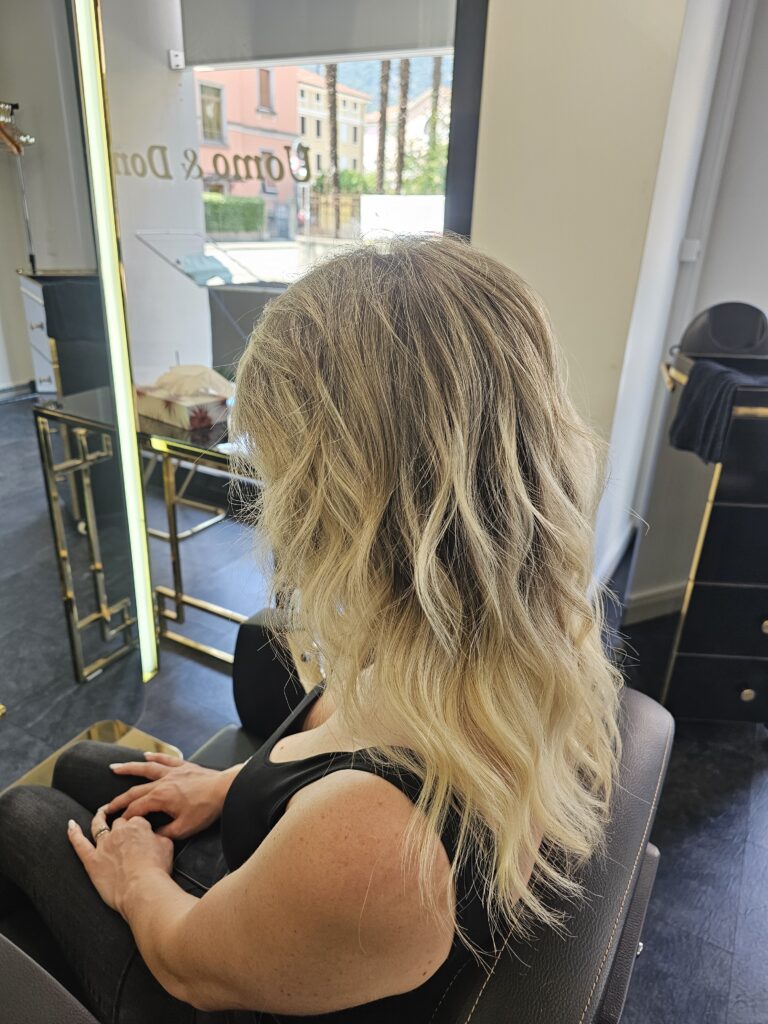 Donna con capelli biondi lunghi e ondulati.