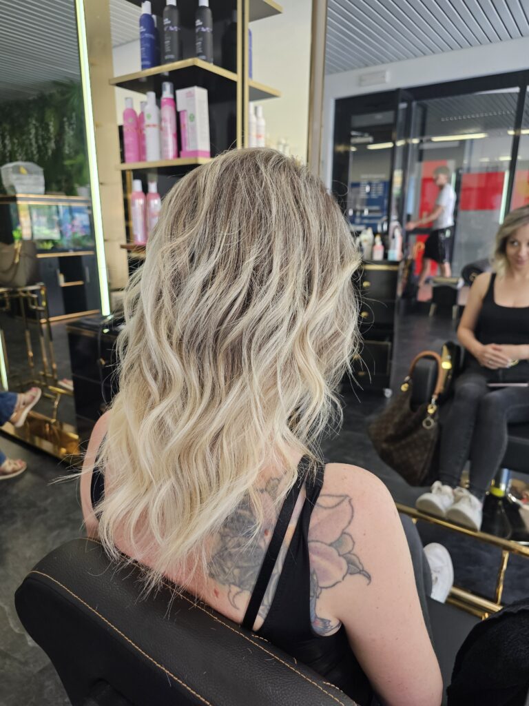 Donna con capelli biondi lunghi e ondulati.