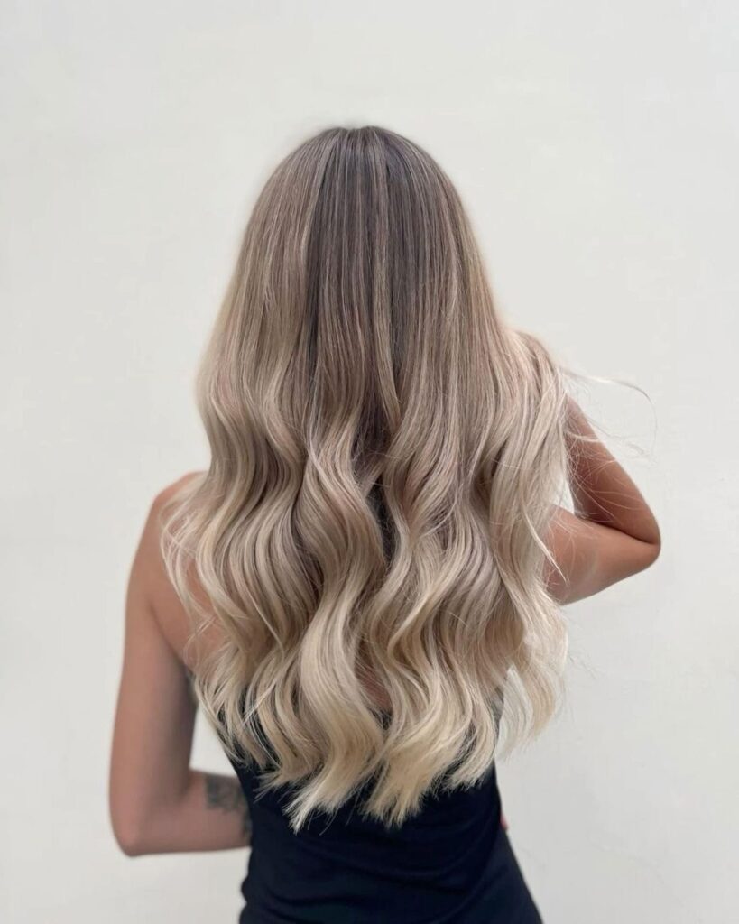 Donna vista di schiena con lunghi capelli biondi e ondulati.