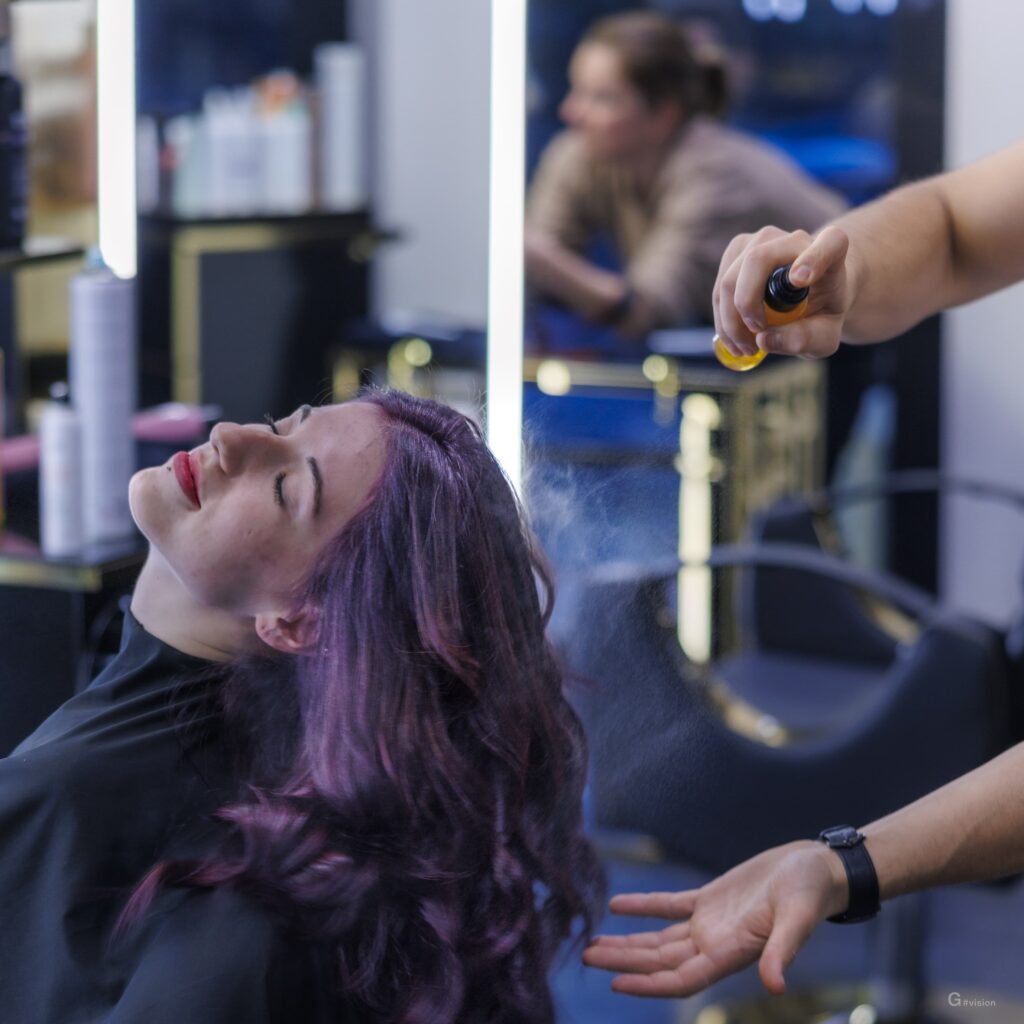 Professionista che spruzza un prodotto sui capelli di una cliente.