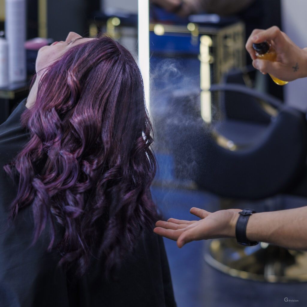 Melark spruzza uno spray sui capelli viola di una donna.